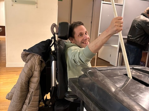 Patrick van de Plas, trouwe vrijwilliger op het stembureau in Den Boogaard in Moergestel, geeft vanuit zijn rolstoel de stembiljetten een duwtje.