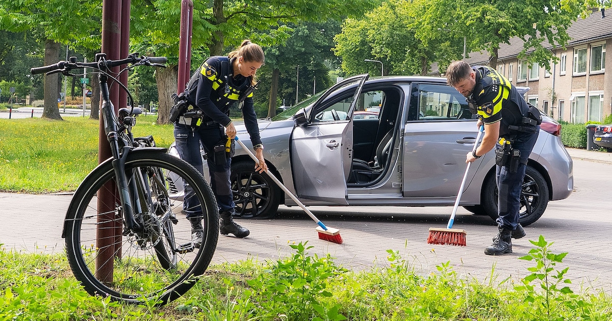 Diepe deuk in portier en lekke band door botsing auto met elektrische fiets, man raakt gewond aan hand.