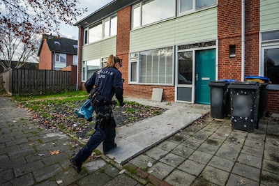 Politie doet inval bij huis in Eindhoven, agenten brengen plastic zakken vol spullen naar buiten
