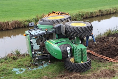 Tractor met aanhanger raakt van de weg en belandt onderaan de dijk in Waspik